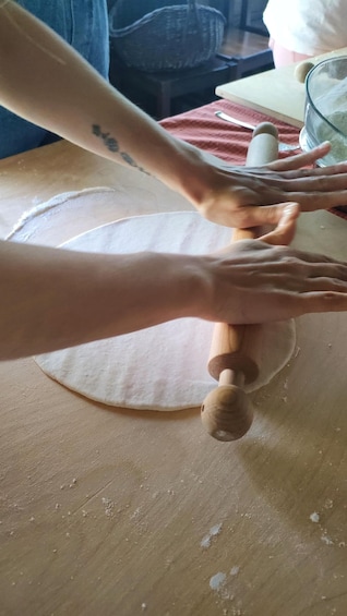 Hands rolling dough on a wooden surface. 4