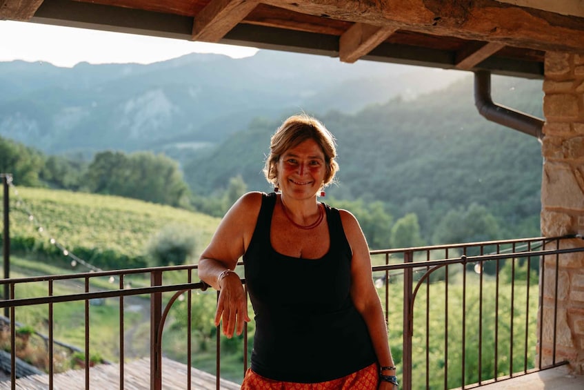 A person standing on a balcony with a mountainous landscape in the background. 2