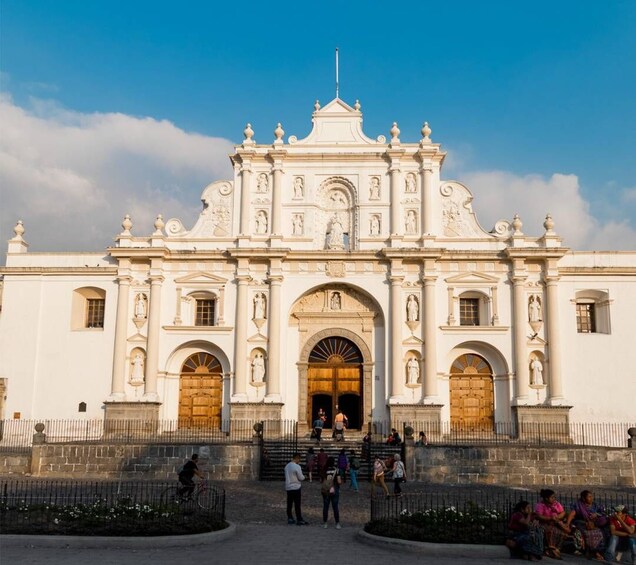 A historic white building with ornate architecture, including a large central archway and multiple statues. 2