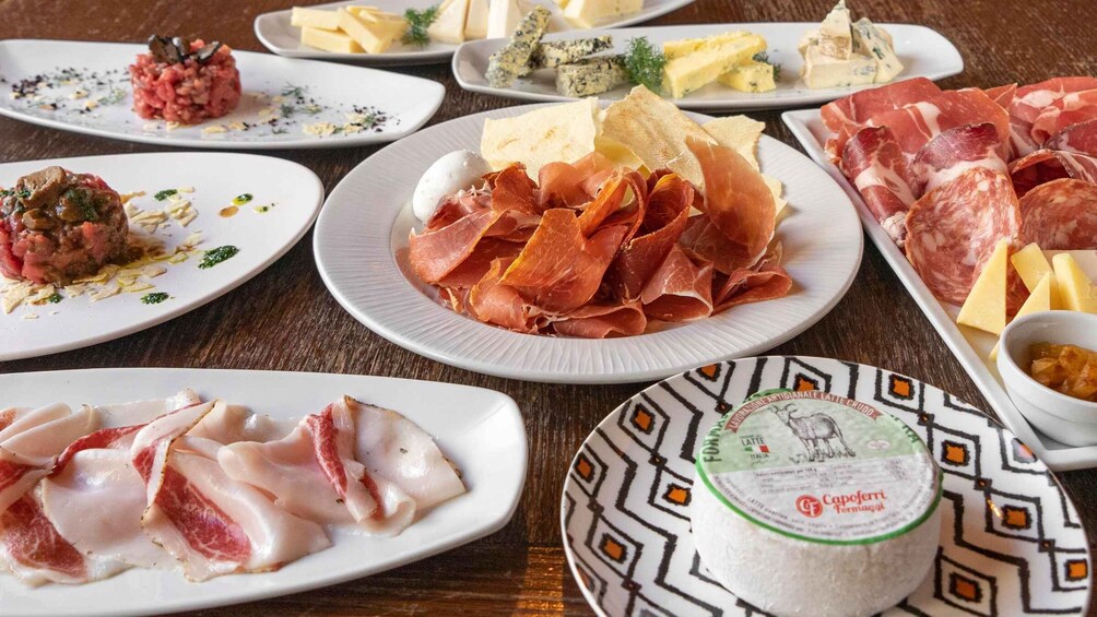 A variety of Italian cheeses, cured meats, and a dish of meatballs. 1