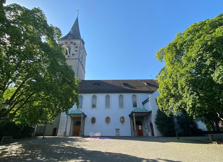 A church with a clock tower, surrounded by trees. 3