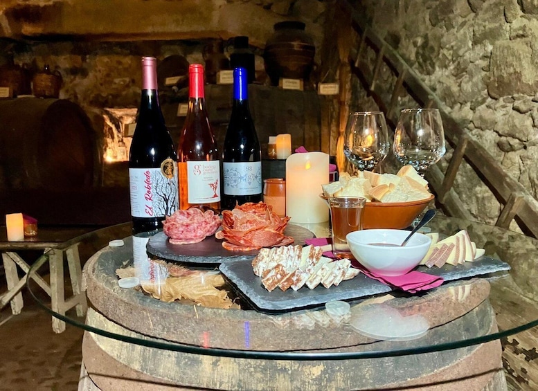 A wine tasting setup with bottles, glasses, and various cheeses and cured meats on a glass table. 2