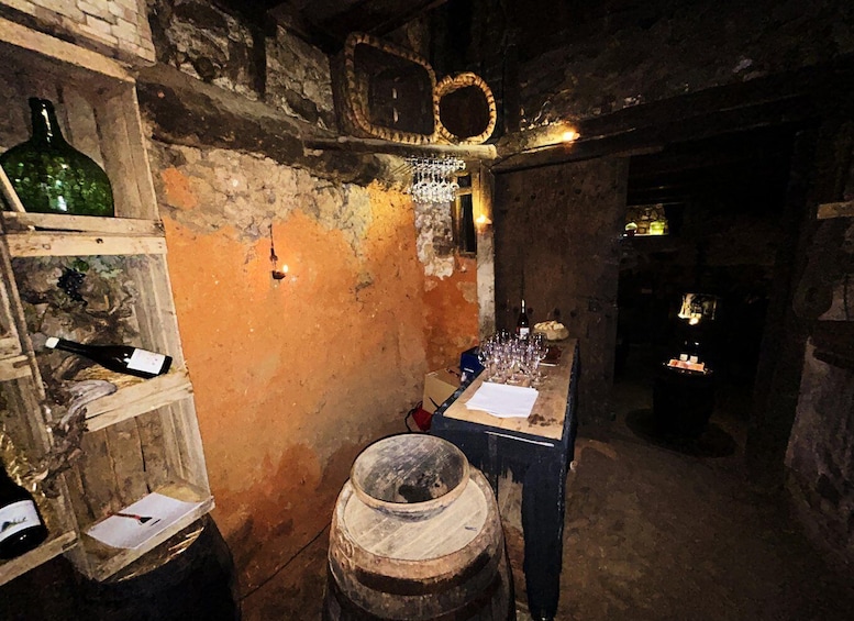 An old cellar with wooden barrels, wine bottles, and a table with glasses. 3