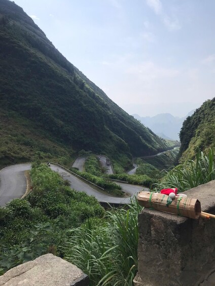 A winding mountain road surrounded by lush greenery and distant mountains. 1