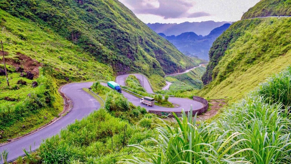 A winding mountain road with vehicles, lush greenery, and a valley. 5