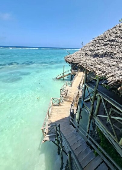 A wooden pier leading to a thatched-roof structure over turquoise waters. 4