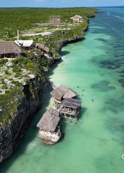 A coastal village with thatched-roof structures and a clear turquoise sea. 5