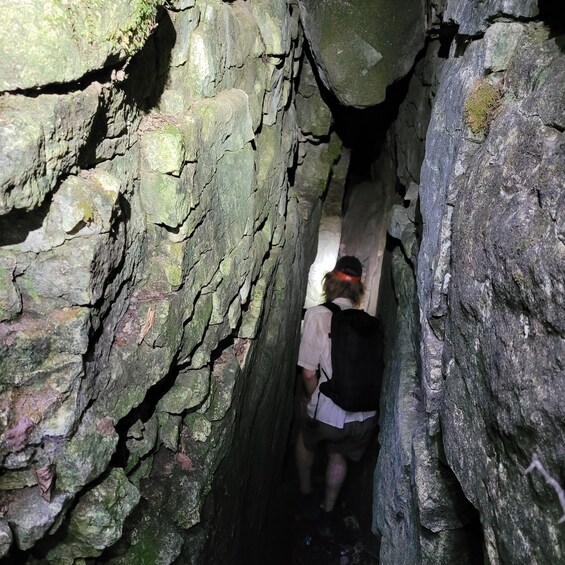 A person walking through a narrow, rocky passageway. 2