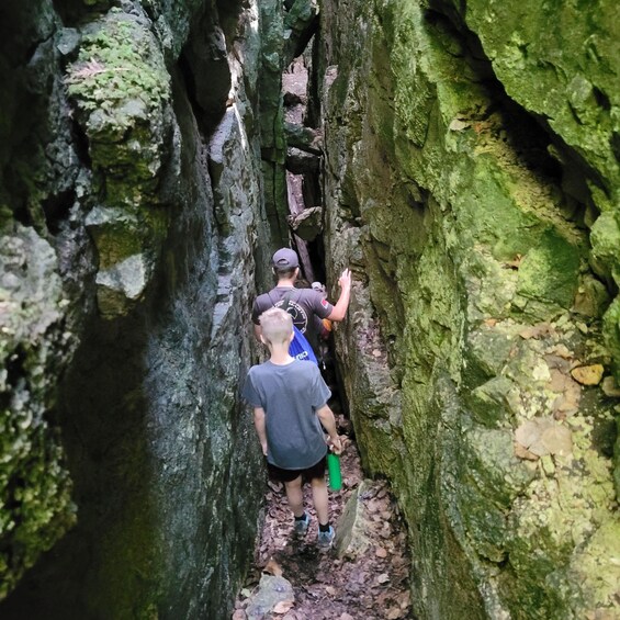 A narrow canyon with hikers navigating through rocky terrain. 1