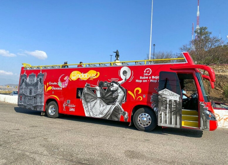 A red bus with Andador and Oaxaca logos, a statue, and a city tour advertisement. 3