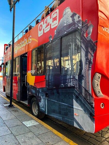 A red double-decker bus with advertisements for city tours and a clock on the side. 5