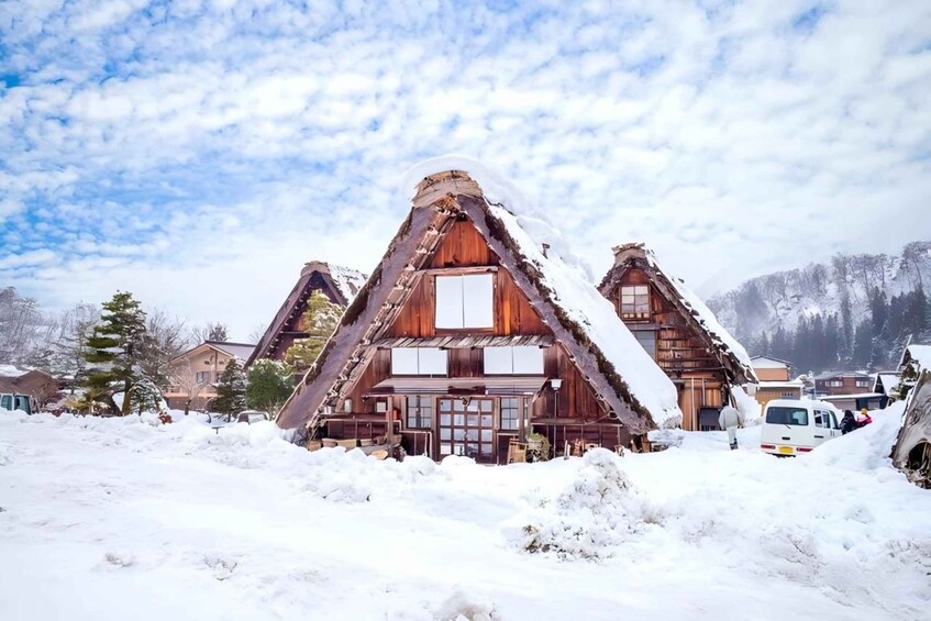 A traditional wooden chalet with a steeply pitched roof, surrounded by snow-covered ground and trees. 5