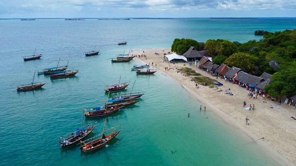 A beach with boats docked and people walking along the shore. 2