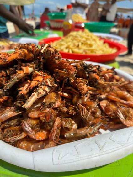 A large white bowl filled with cooked crabs, a red bowl of fries, and a green bowl in the background. 3
