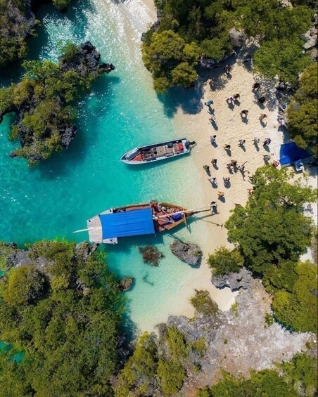 A tropical beach with two boats anchored near the shore, surrounded by lush greenery and clear turquoise waters. 4