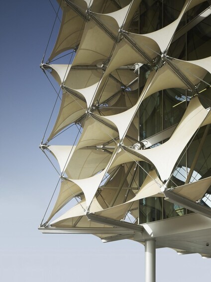 A modern architectural structure with a series of white, sail-like elements. 1