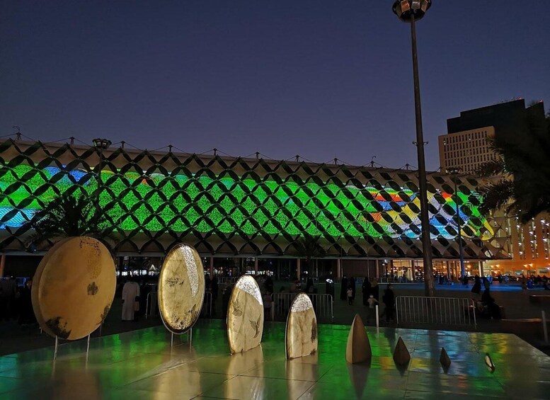 A plaza with a large, illuminated geometric structure and several large, round sculptures. 5