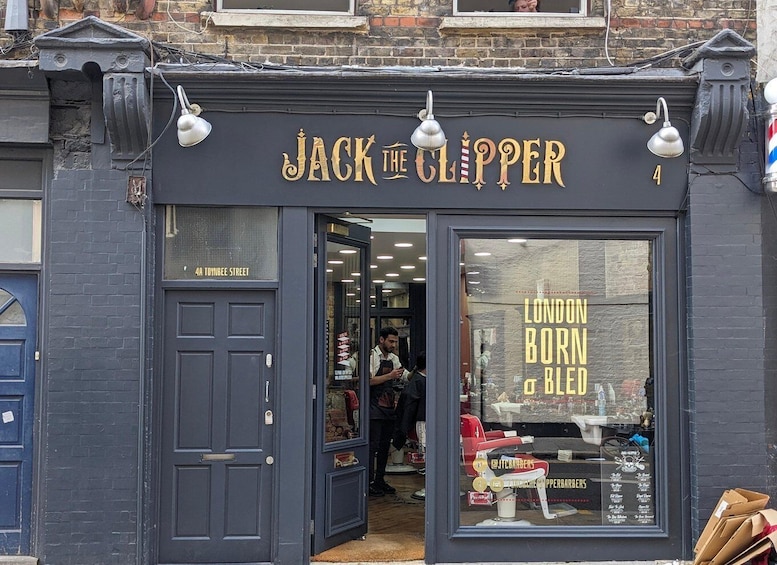 A storefront with a dark facade, the name 'JACK THE CLIPPER' in gold lettering, and a large window displaying 'LONDON BORN & BLED' in yellow. 2