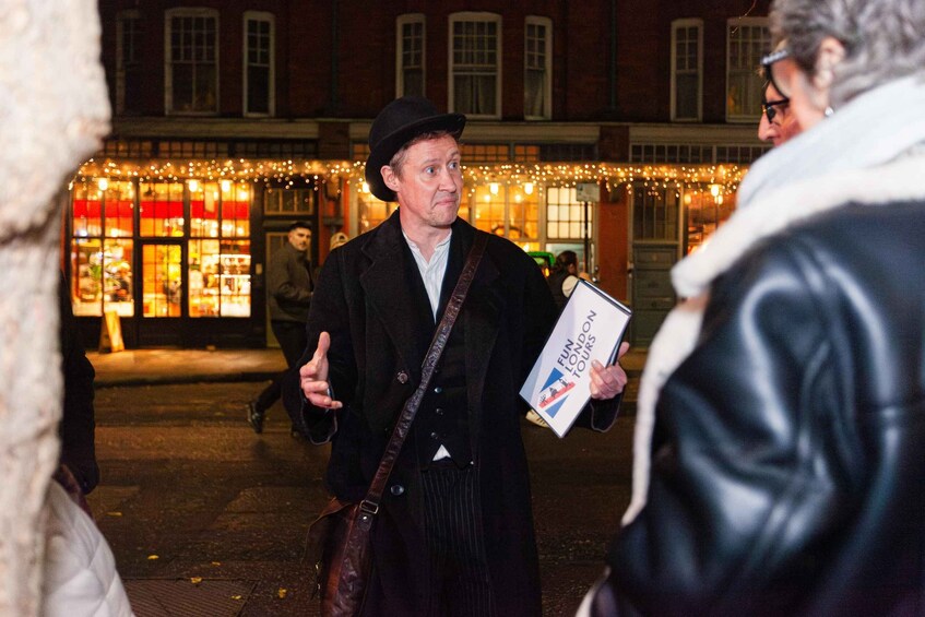 A person holding a brochure with 'FUN LONDON TOURS' written on it, standing on a street with buildings in the background. 4