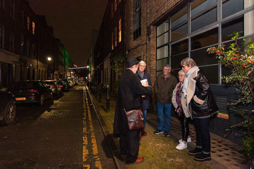 A group of people standing on a city street at night. 3