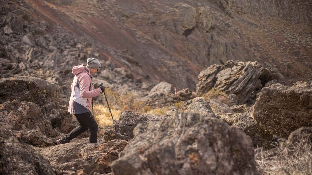 A person hiking on rocky terrain with a walking stick. 1