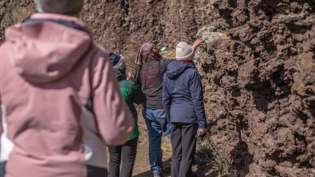 A group of people examining volcanic rock formations. 4