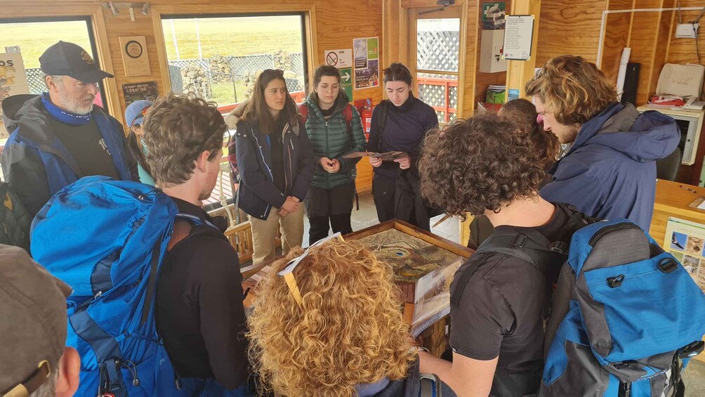A group of people gathered around a table with a large, curly-haired wig on display. 3