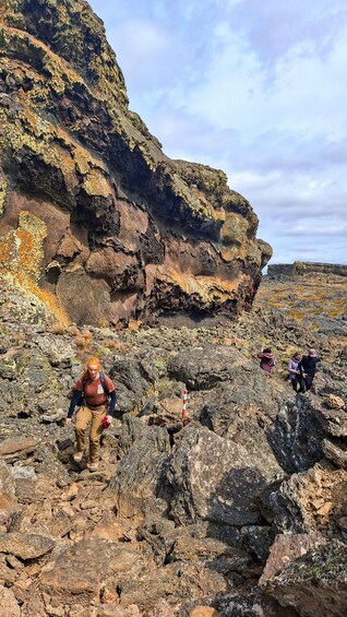 Hikers on rocky terrain with a cliff in the background. 2