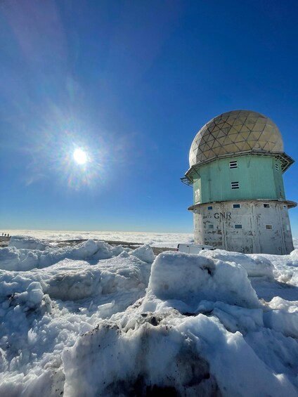 A weather station with a dome on top, surrounded by snow. 1