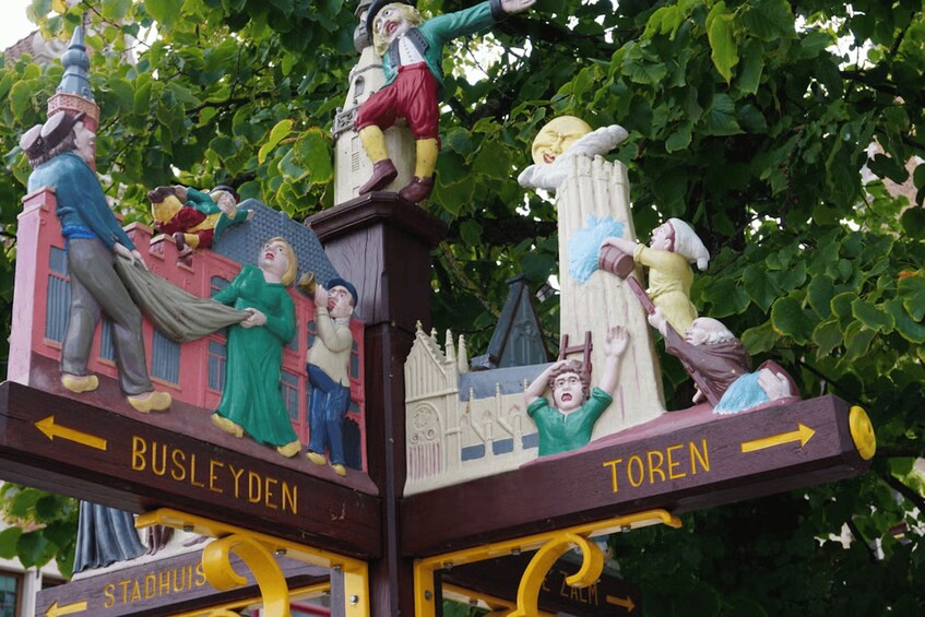 A wooden sign with figures and directional arrows pointing to 'Busleyden' and 'Toren'. 2