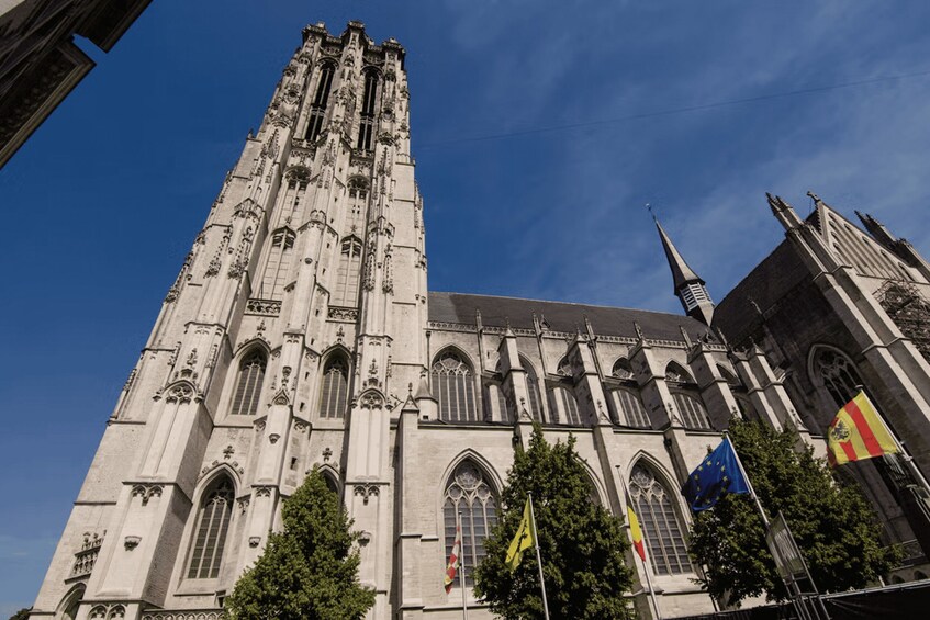 A tall Gothic cathedral with intricate architectural details, a spire, and flags. 3