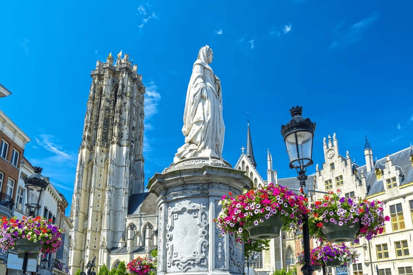 A statue in a square with gothic architecture in the background. 1