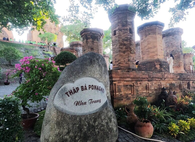 A stone monument with inscriptions, surrounded by potted plants and ancient stone structures. 1