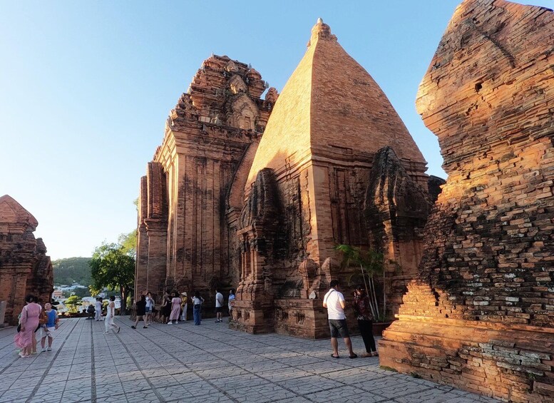 Ancient brick structures with a central pyramid-like building and smaller surrounding buildings. 3