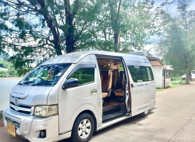 A white van parked on a paved area with trees in the background. 2