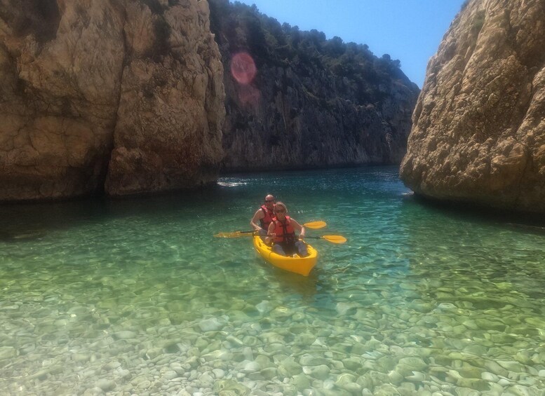Una persona haciendo kayak en aguas cristalinas, rodeada de acantilados rocosos. 1