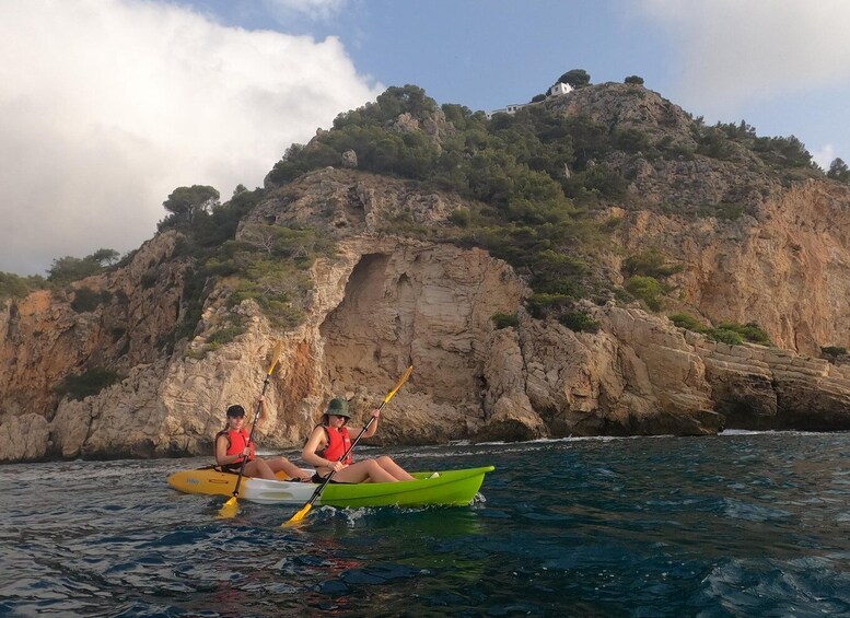 Dos personas kayak en un mar tranquilo con un acantilado rocoso al fondo. 3