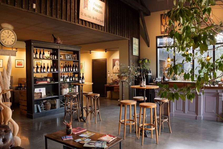 A cozy bar with wooden shelves stocked with bottles, a clock, and a sign reading 'Frederic Mabileau St Nicolas de Bourgogne.' 1