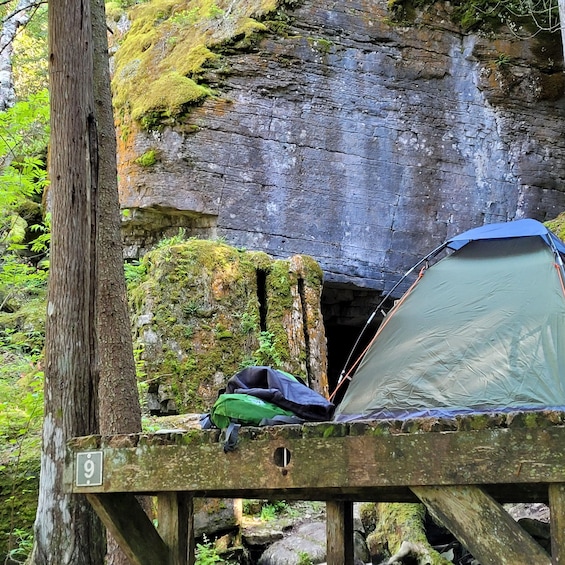 A tent set up on a wooden platform with a rocky cliff in the background. 5