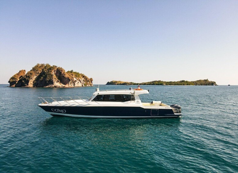 A boat named 'COMO' on calm waters with rocky islands in the background. 1