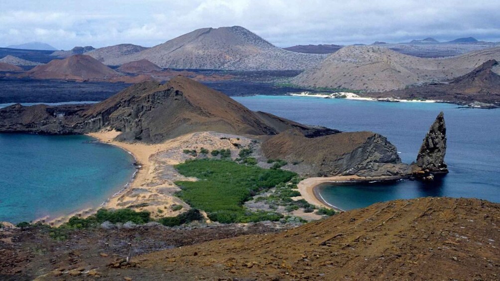 A coastal landscape with a prominent mountain, a small beach, and a clear blue sea. 2