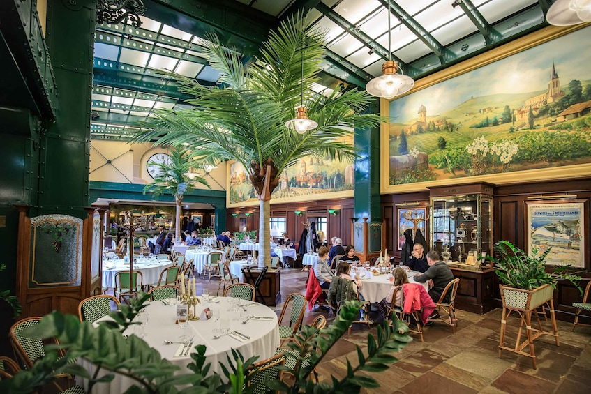 A restaurant with round tables, chairs, and a large palm tree. 3