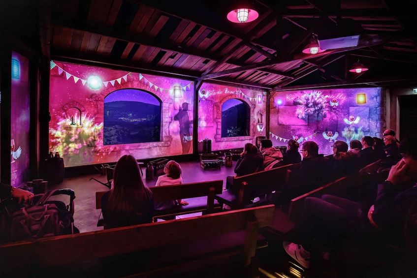 An indoor venue with a stage, audience seating, and decorative elements like bunting and lanterns. 5