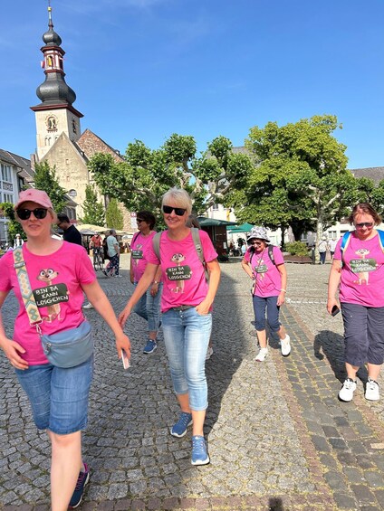 People walking on a cobblestone street with a church tower in the background. 1