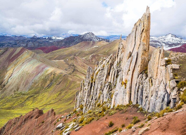 A rugged mountain landscape with a prominent rock formation in the foreground and snow-capped peaks in the background. 3