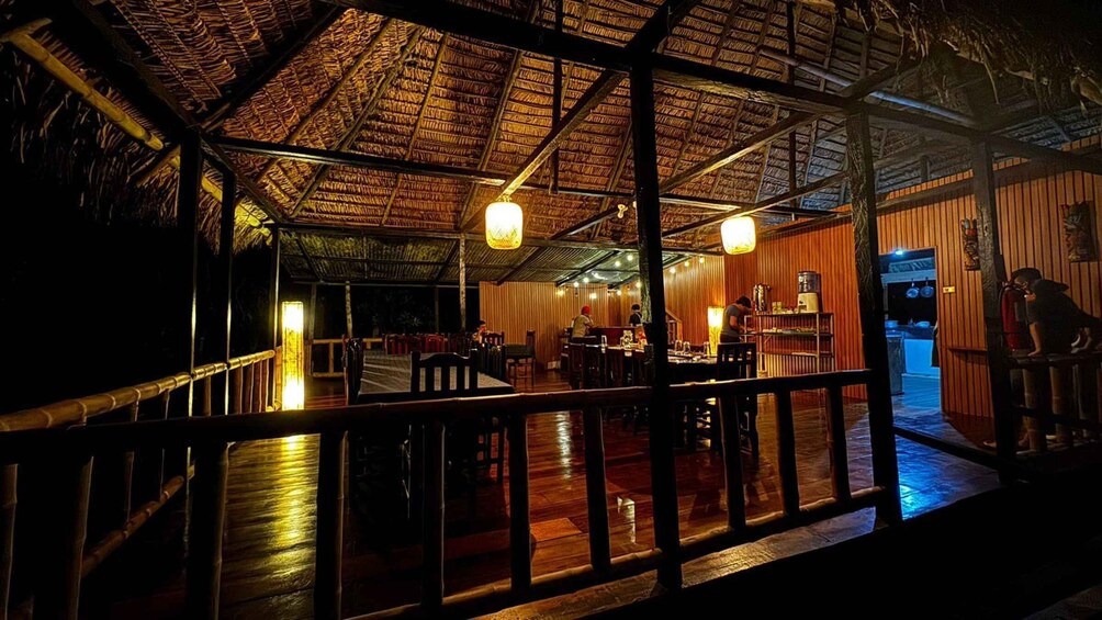 An indoor restaurant with wooden beams and a thatched roof. 3