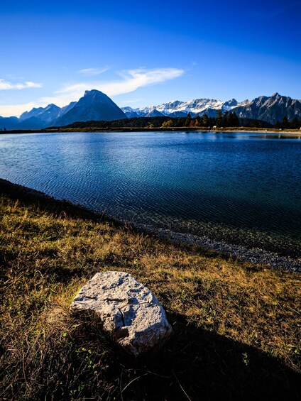 A lake with mountains in the background and a large rock in the foreground. 4