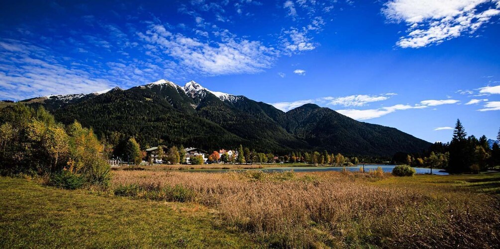 A mountain range with snow-capped peaks, a lake, and a village with houses. 5