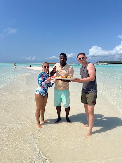 Three people on a beach holding a plate with food. 4