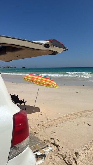 A beach with a car and a colorful umbrella. 3